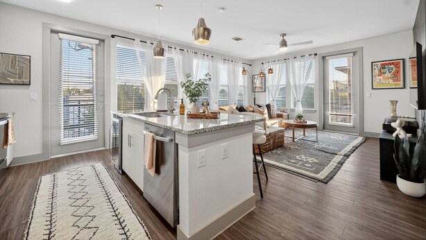 A spacious kitchen with a central island, large windows, and modern pendant lighting. - Rhythm Room | Oak Lawn 2BR Near Uptown, Pool & Gym (Dallas)