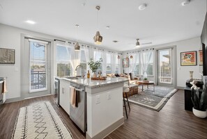 Une cuisine spacieuse dotée d’un îlot central, de grandes fenêtres et d’un éclairage moderne suspendu au plafond.