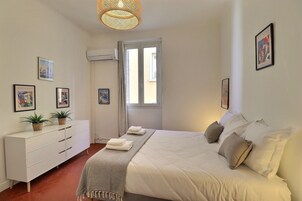 Un dormitorio con cama, cómoda blanca y decoración en la pared.