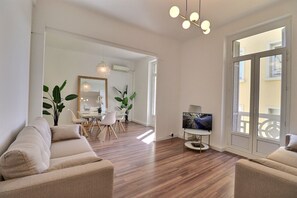 Ένα σύγχρονο σαλόνι με έναν καναπέ, μια τηλεόραση και μια τραπεζαρία με καρέκλες και ένα τραπέζι.