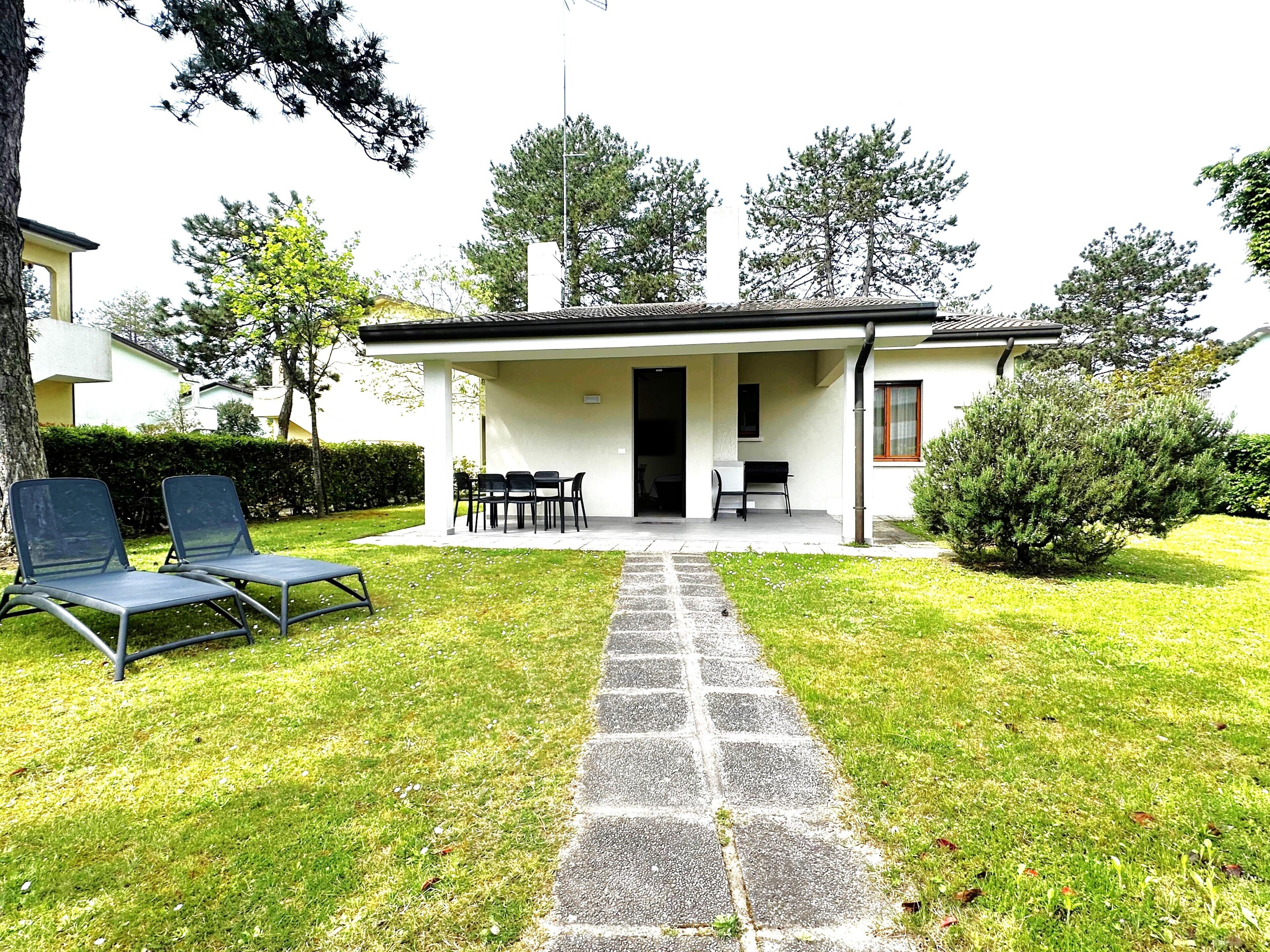 Une maison dotée d’un patio couvert, d’un chemin en pierre menant à l’entrée et d’un espace salon extérieur.