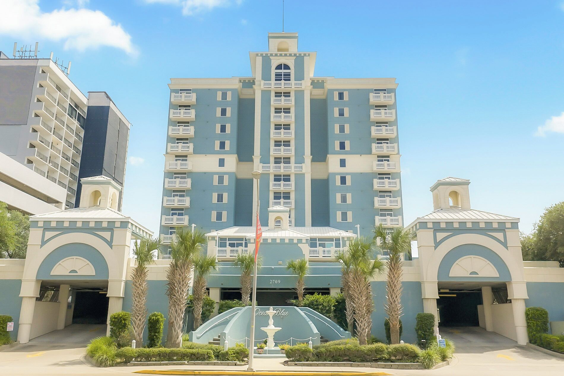 A multi-story hotel with a central atrium, palm trees, and a fountain.