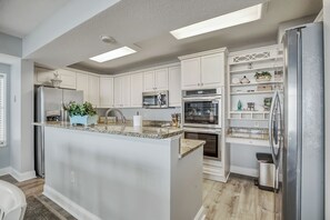 A modern kitchen with white cabinetry, stainless steel appliances, and a central island.