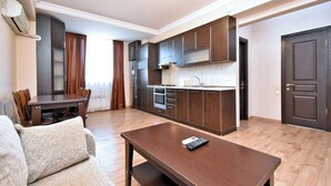 Un appartamento moderno con zona pranzo, angolo cottura e soggiorno con divano e tavolino.