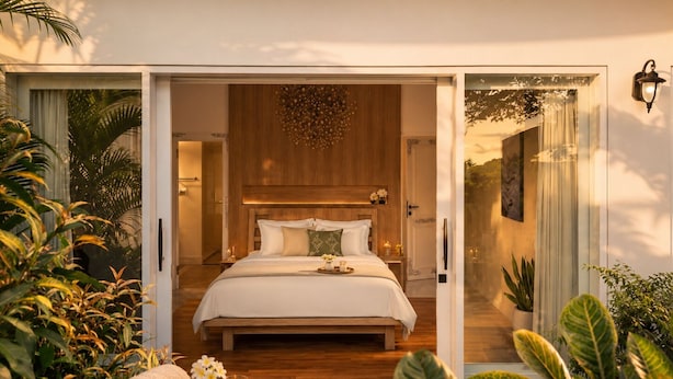 Une chambre moderne avec un grand lit, une tête de lit en bois et une vue sur un jardin.