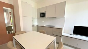 Eine moderne Küche mit Essbereich, inklusive Tisch, Stühlen, einer Mikrowelle und einem Flachbildfernseher.