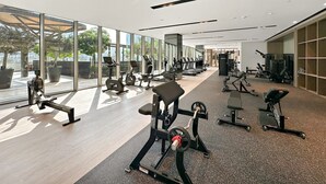 Uma academia moderna com diversos equipamentos de ginástica, amplas janelas e vista para o exterior.