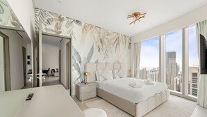 Quarto de hotel moderno com uma cama grande, uma escrivaninha e vista para a cidade.