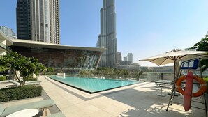Uma área de piscina no terraço com espreguiçadeiras, um flutuador de salva-vidas e vista para o Burj Khalifa.
