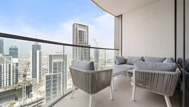 Uma varanda com vista para um horizonte urbano, exibindo edifícios modernos e uma grua de construção.