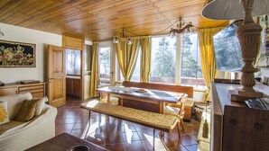 Un plafond en bois, une table à manger avec des chaises, un banc, un canapé et une lampe.