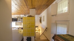 Un escalier avec une rampe en bois, un meuble mural jaune et un lit recouvert d’une couverture verte.