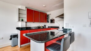 Una cocina moderna con gabinetes rojos, una encimera de granito negro y una isla integrada con asientos.
