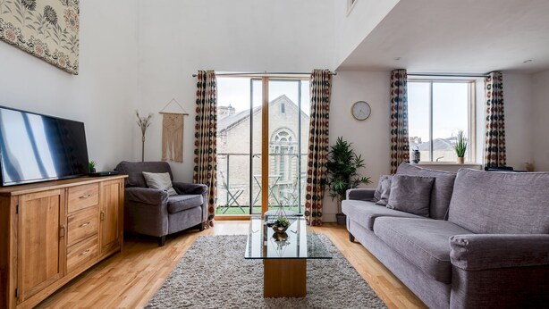 Una sala de estar moderna con un sofá, una mesa de centro y un televisor sobre un mueble de madera.