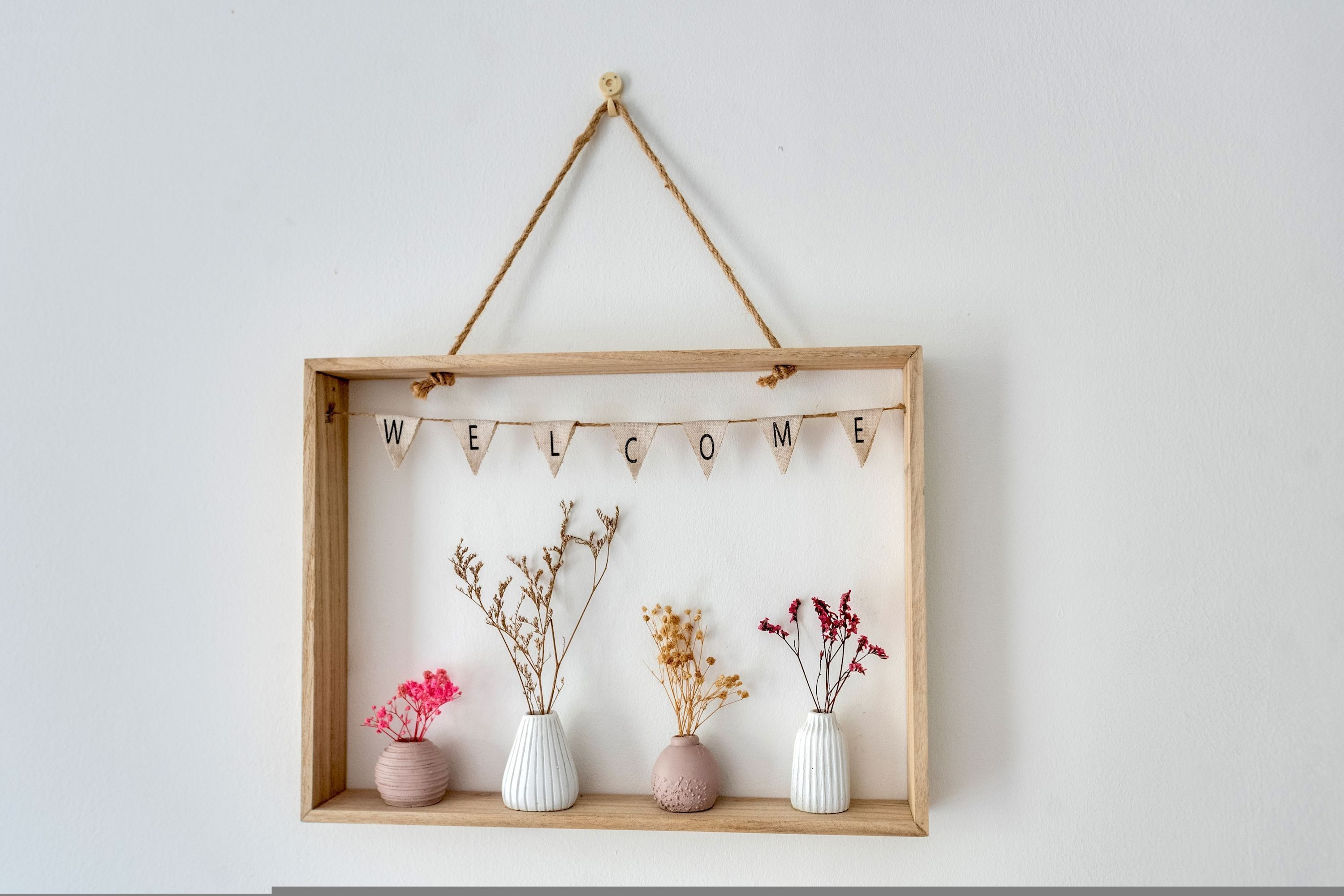 A welcome sign with a wooden frame and a string of letters spelling "WELCOME" above it.