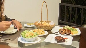 A dining table with various dishes, including a salad, fries, and meat, along with a basket and a cup.