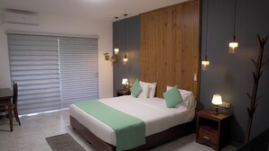 A modern bedroom with a large bed, bedside tables with lamps, a wooden panel wall, and a sliding door.