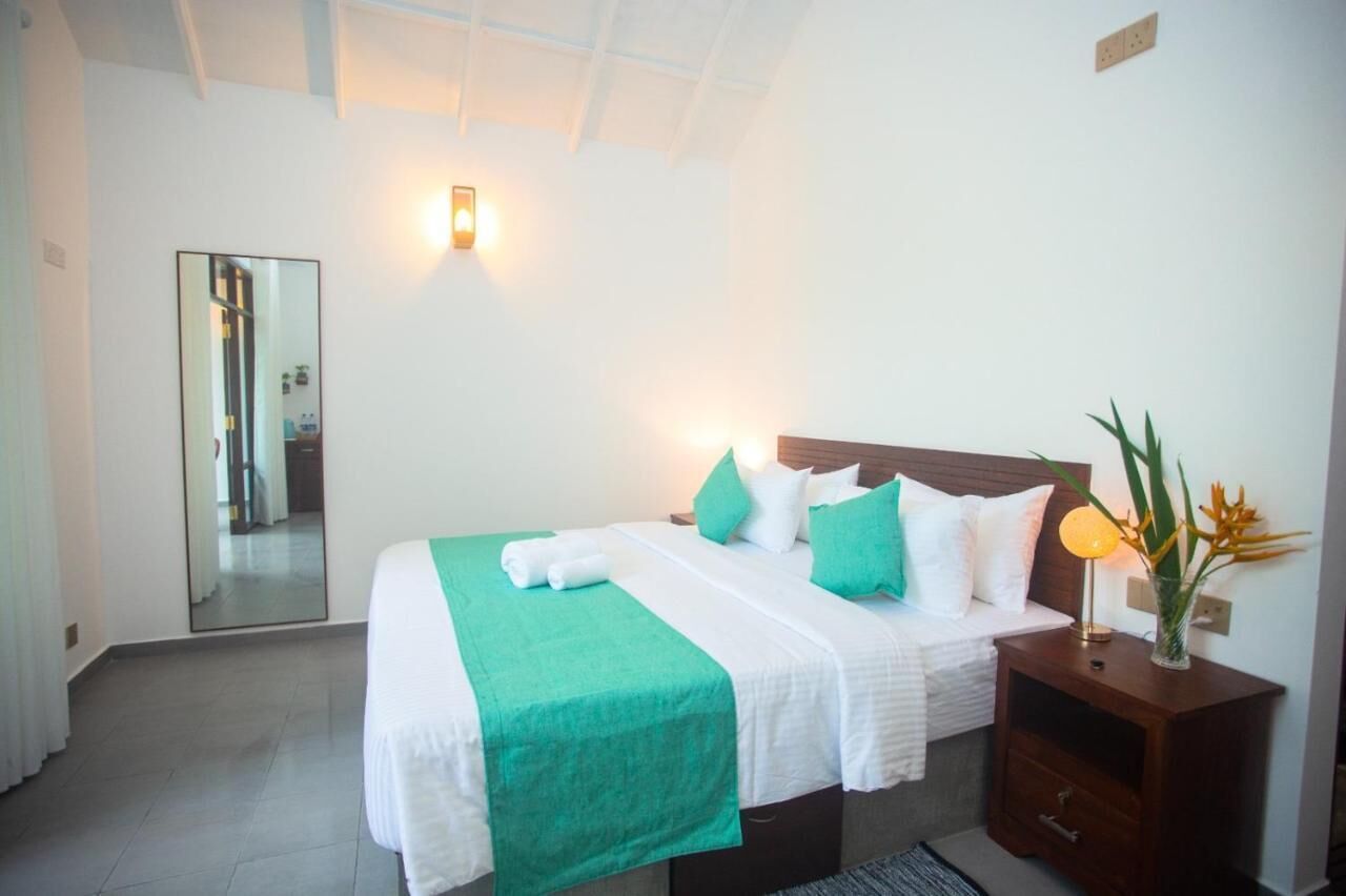 A hotel room with a bed, bedside table, lamp, and a mirror.