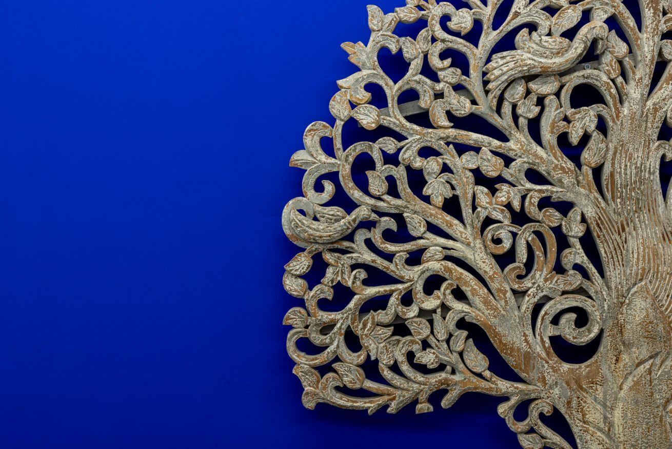 A detailed, ornate metalwork piece with intricate designs, set against a solid blue background.