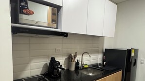 A modern kitchen with a black countertop, wooden cabinets, a stainless steel sink, and a black refrigerator. - Studio in Bogotá with the best location and view. (Bogotá, D.C.)