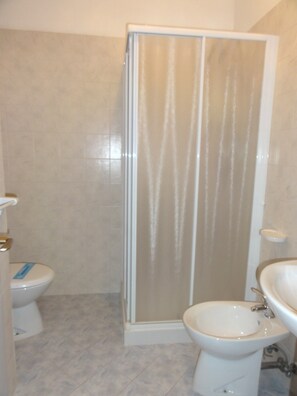 Egy fürdőszoba, amelyben WC, bidé és zuhanyzó található.