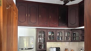 A kitchen with dark wooden cabinets, a stainless steel refrigerator, and a ceiling fan. - Tranquil 2-Bedroom Haven with AC near Varkala North Cliff (Varkala)