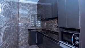 A modern kitchen with a marble backsplash, stainless steel appliances, and a window with decorative ironwork.