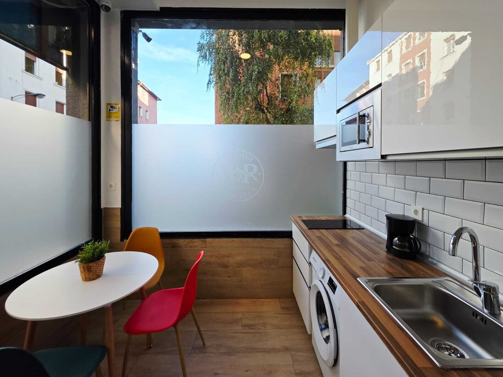 Een kleine keuken met een wasmachine, koffiezetapparaat en magnetron.
