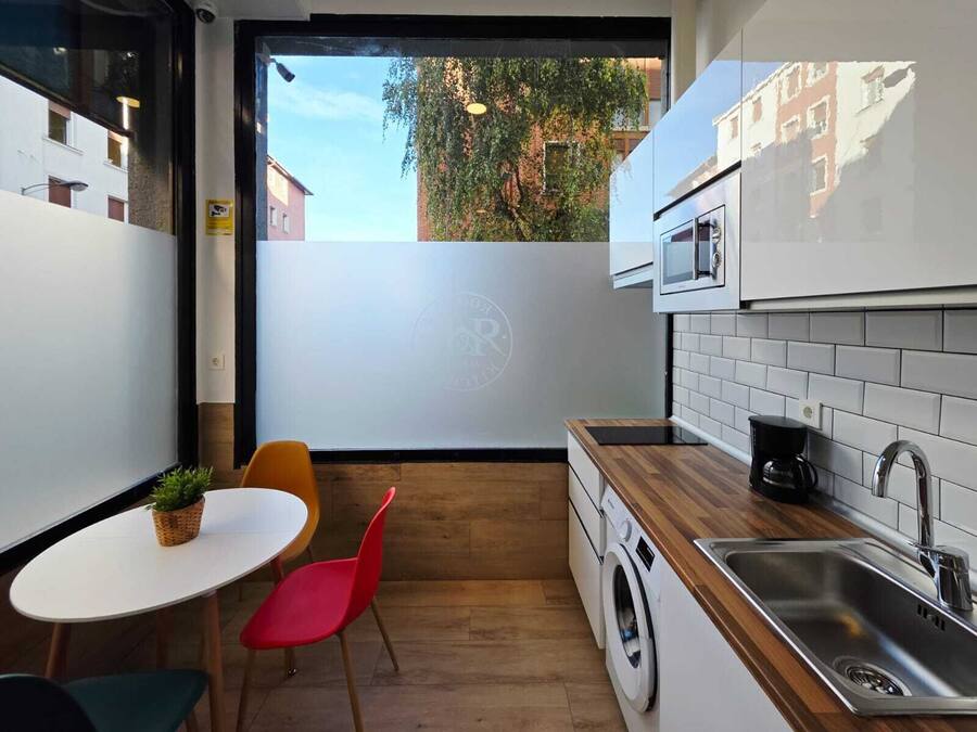 Una cocina funcional con lavadora, cafetera y microondas.