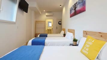 Een hotelkamer met twee bedden, een televisie, een schilderij en een kussen met een motiverende spreuk.