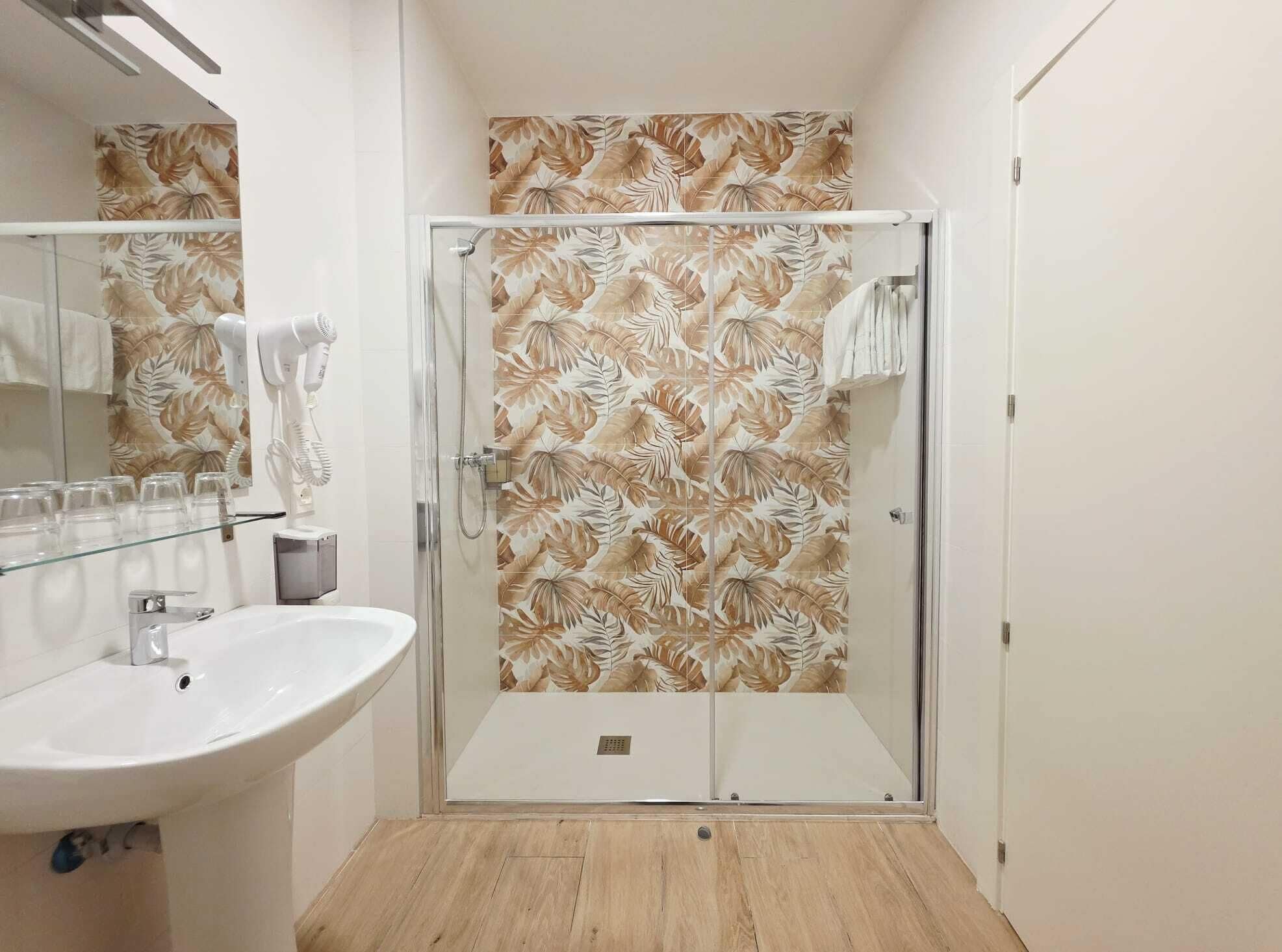Un baño con cabina de ducha de vidrio, lavamanos y espejo.