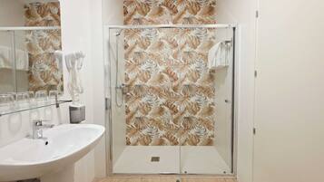Un baño con cabina de ducha de vidrio, lavamanos y espejo.