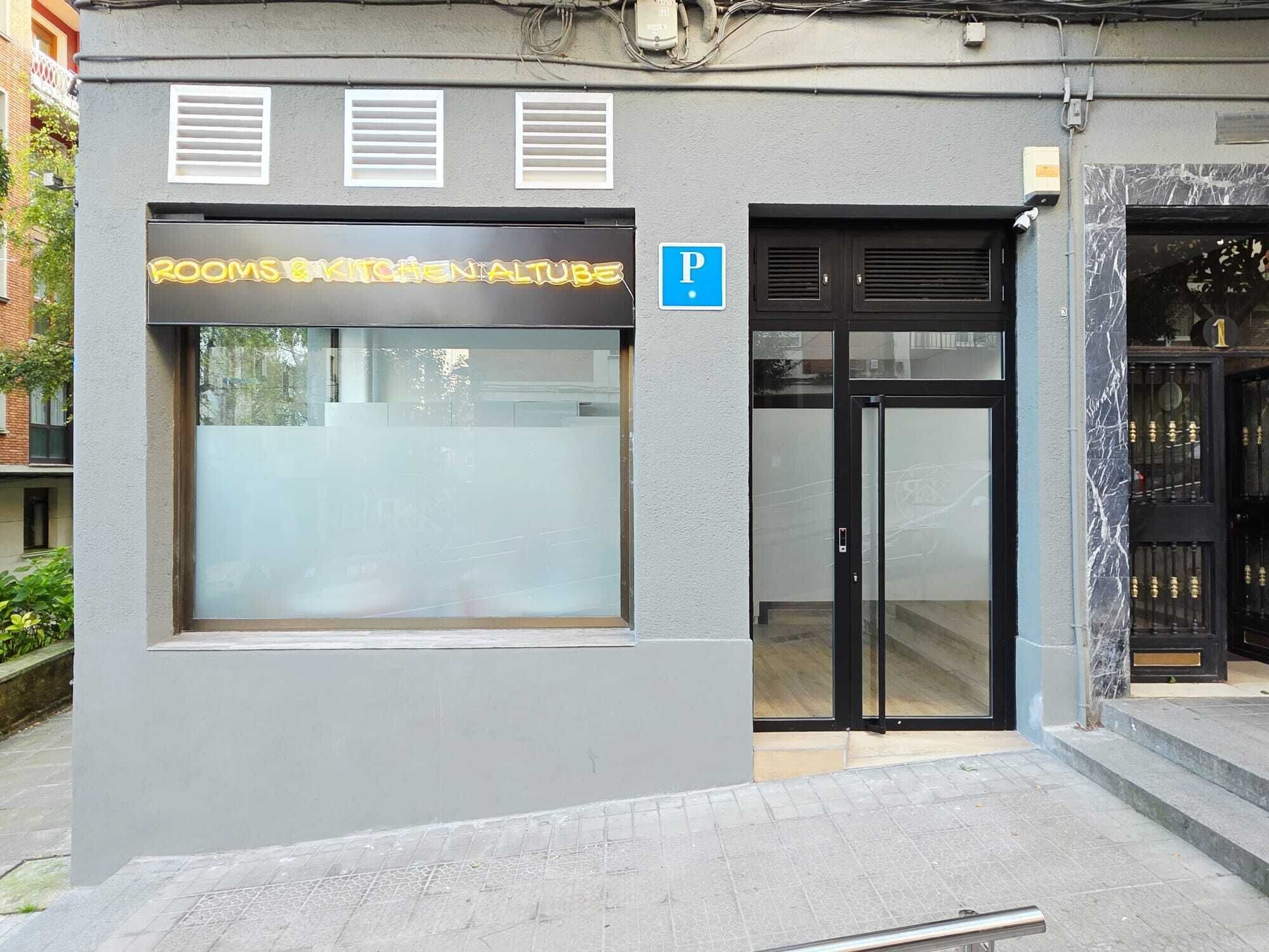 Um edifício com uma placa indicando 'Rooms & Kitchen Altube' e um aviso de estacionamento.