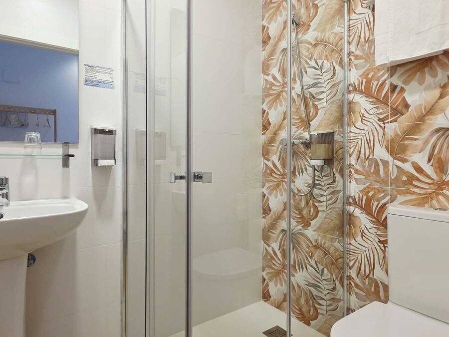 Un baño con cabina de ducha de vidrio, lavamanos y retrete.