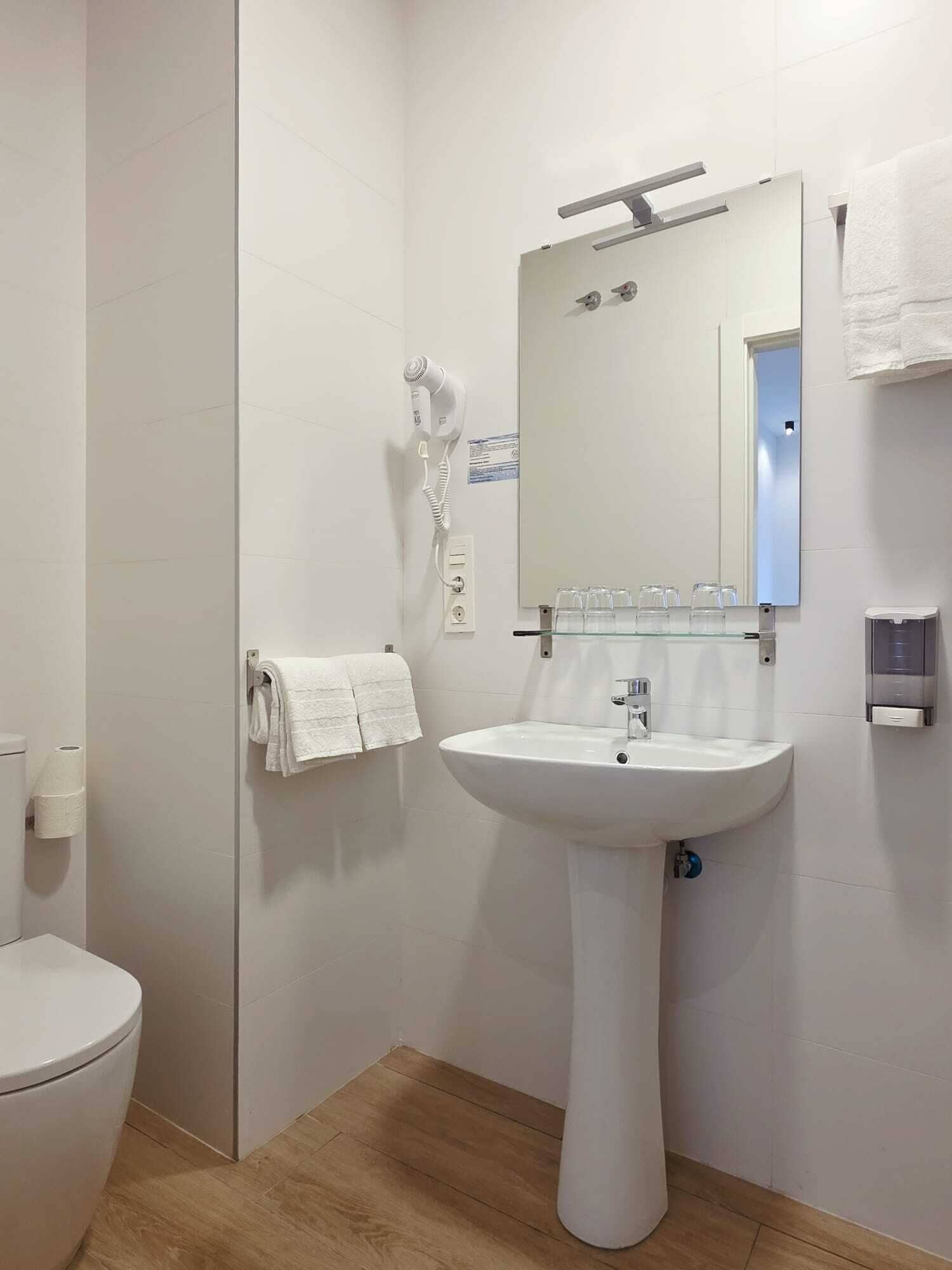 A bathroom with a white sink, mirror, and towel rack.