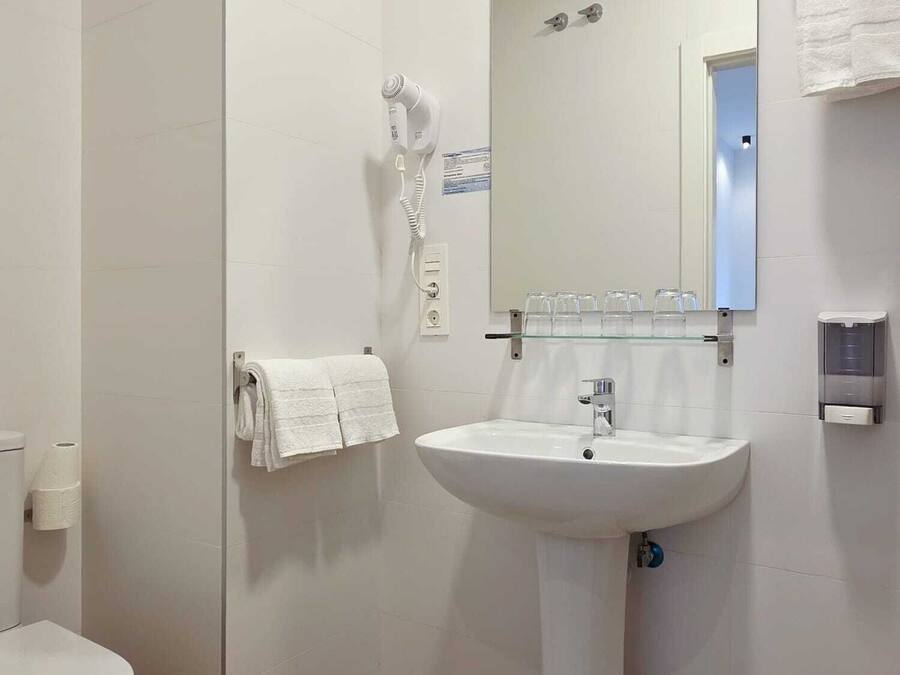 A bathroom with a white sink, mirror, and towel rack.