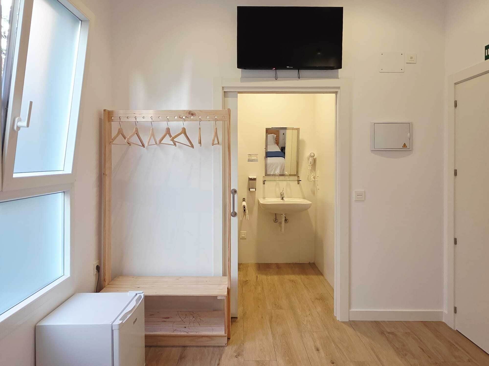 Un dormitorio con cama, televisión, baño con lavamanos y zona de ducha.