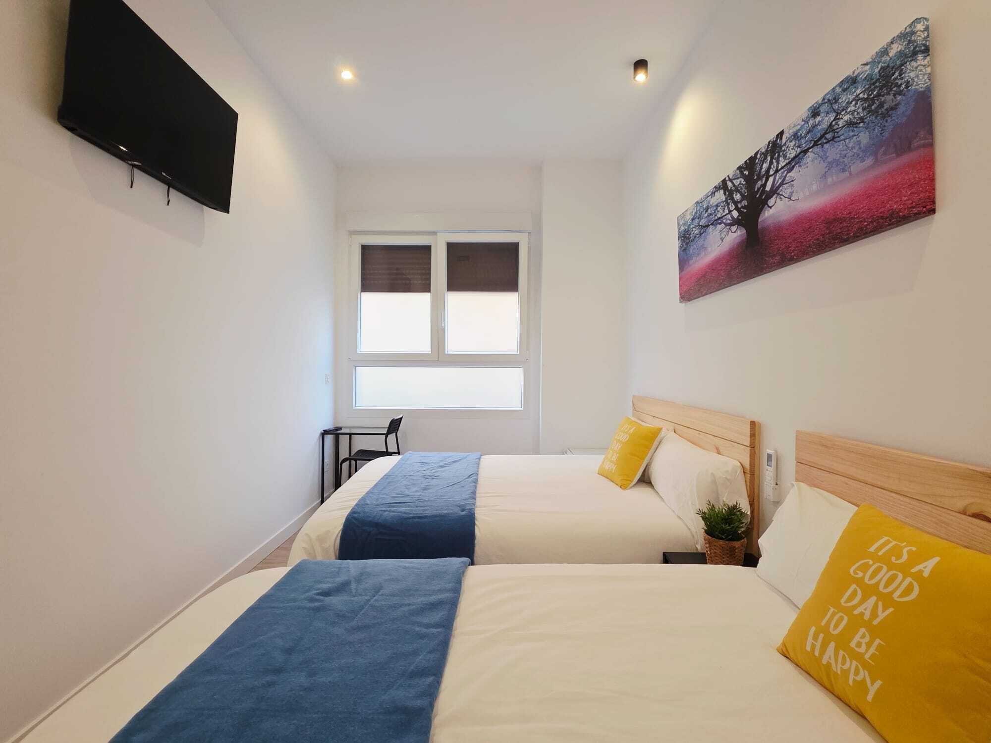 Habitación de hotel con dos camas, un televisor, una ventana y un cuadro.