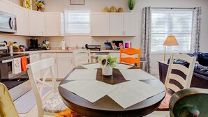A modern kitchen with white cabinets, a dining table with placemats, and a coffee maker. - 9 Minutes to fort, 15 Minutes to sand-fenced yard (St Augustine)