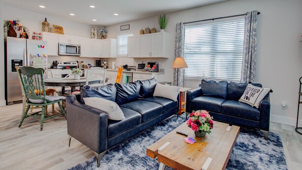 A modern living room with a sofa, coffee table, and a dining area with a table and chairs. - 9 Minutes to fort, 15 Minutes to sand-fenced yard (St Augustine)
