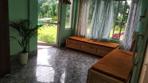 A room with a bench, a potted plant, and a window with curtains. - Infinity Viewpoint Homestay (Kalimpong)