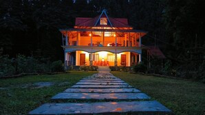 A two-story building with a central balcony, a covered porch, and a pathway leading to the entrance. - Infinity Viewpoint Homestay (Kalimpong)