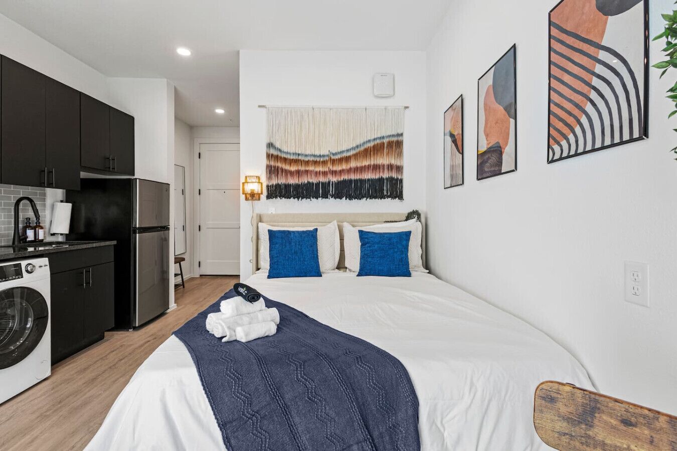 Een moderne hotelkamer met een bed, een kitchenette en een badkamer.