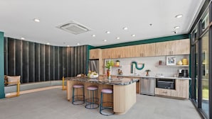 Une cuisine moderne dotée d’un îlot central, de tabourets de bar, de meubles en bois et d’une grande fenêtre offrant une vue dégagée.