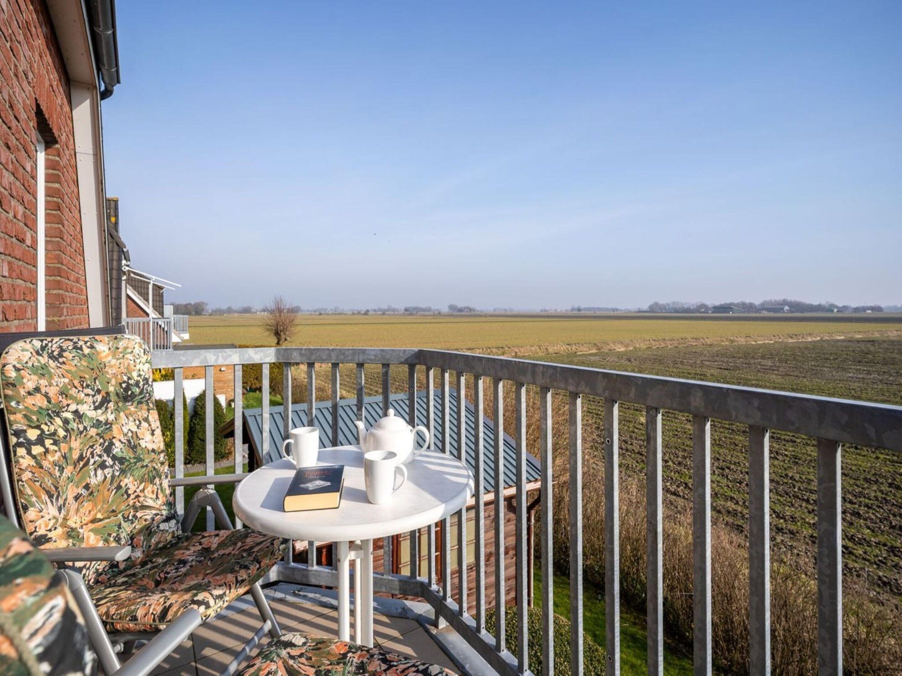 Un balcon avec une table, des chaises et une vue sur un champ.