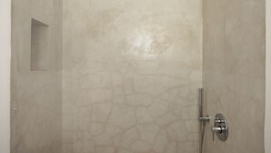 Een badkamer met een structuurwand, een douchegedeelte en een klein plankje.