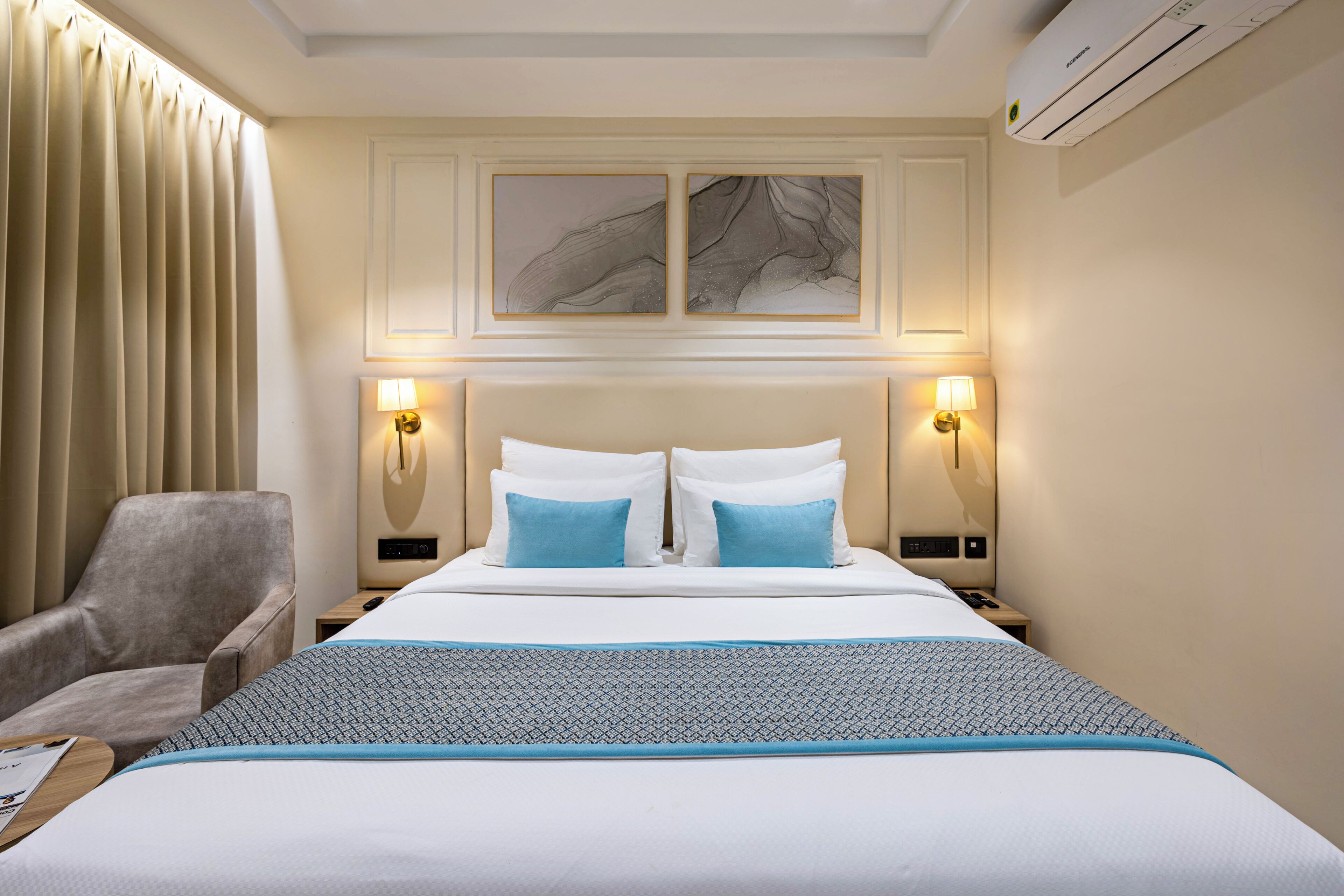 Une chambre d’hôtel comprenant un lit, deux lampes de chevet, une chaise et un climatiseur fixé au mur.