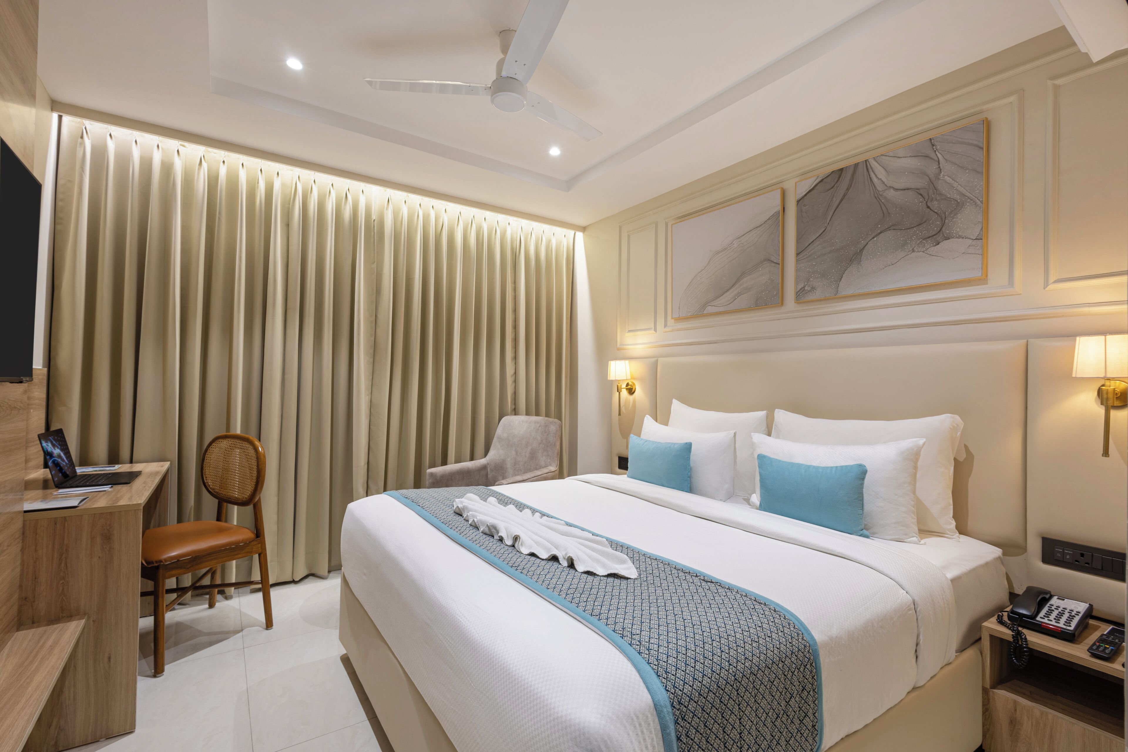 Habitación de hotel con cama, escritorio, silla y una obra de arte en la pared.