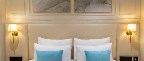 Habitación de hotel con una cama grande, dos lámparas de pared y una obra de arte sobre la cama.