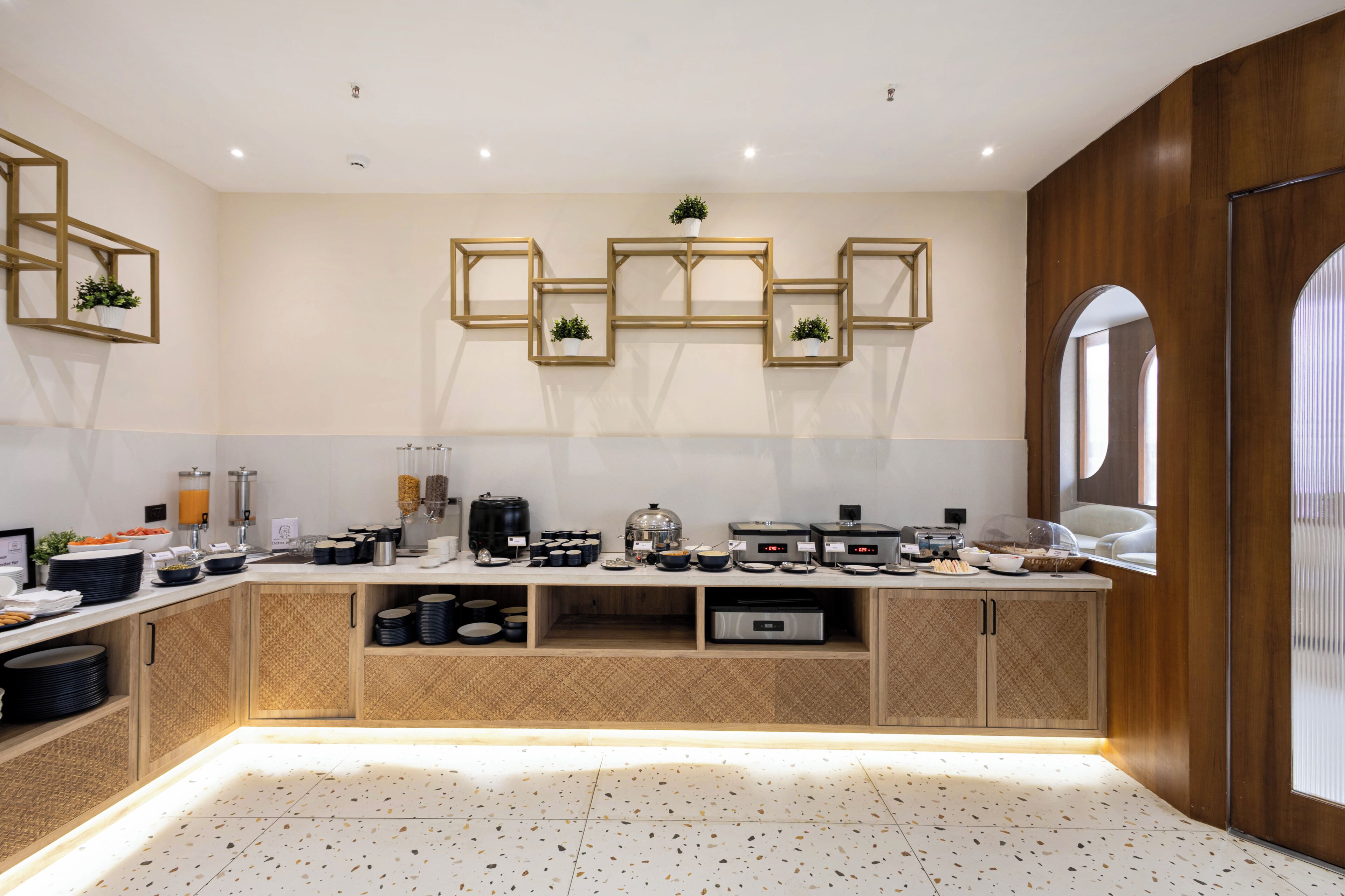 A modern kitchen with built-in appliances, wooden cabinetry, and a speckled floor.